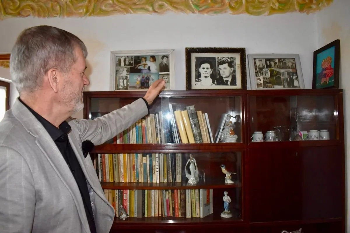 Valeriu Iftime în casa părintească din Zlătunoaia, arătând fotografiile de familie